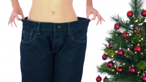 Тощая женщина похудела после рождественских каникул, похудела и похудела. Худышка показывает потерю веса и старые большие джинсы. Сокращение во время праздников, Новый год резолюции диеты
 - Кадры, видео