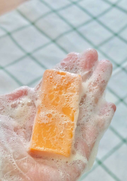 Zblízka žena ruka s oranžové mýdlo bar - Fotografie, Obrázek