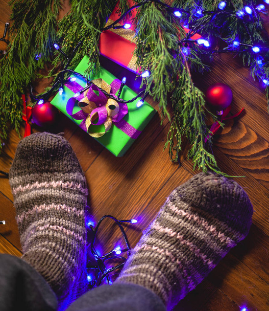 I stand in knitted socks near the Christmas tree with gifts. - Photo, Image