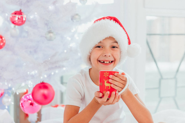 Closeup shot of funny child drinking hot chocolate, loooking at the camera delighted and pleased over white background. - 写真・画像