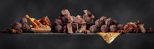 Chocolade met ingrediënten en specerijen op een donkere achtergrond.  - Foto, afbeelding