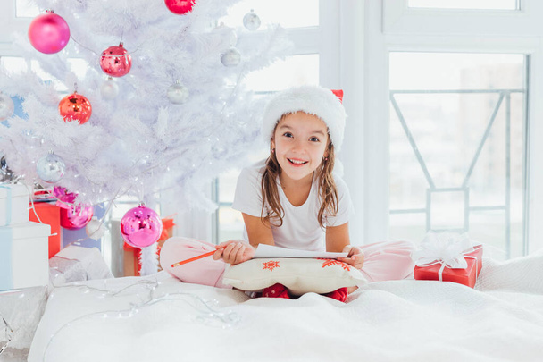 Expressive little girs is showing with gestures and face expression that mailing with santa is really interesting experience. - Zdjęcie, obraz