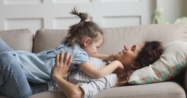 Happy carefree mother and cute child daughter tickling on sofa - Footage, Video