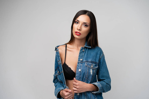Beautiful caucasian girl in a denim jacket posing in the studio on a white background. - Photo, image