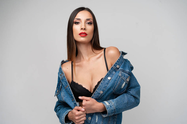 Beautiful caucasian girl in a denim jacket posing in the studio on a white background. - Photo, Image