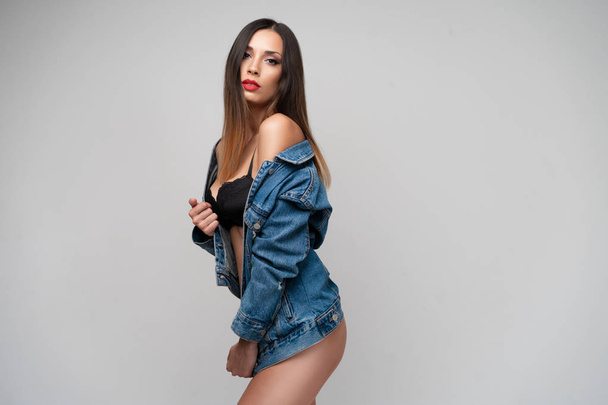 Beautiful caucasian girl in a denim jacket posing in the studio on a white background. - 写真・画像