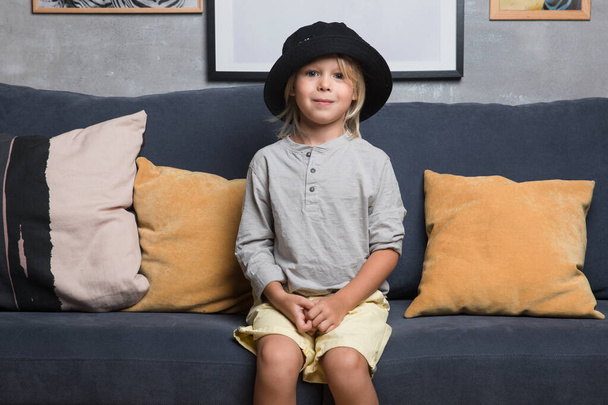 The boy sits on the blue sofa and show different emotions. Kids - Photo, Image