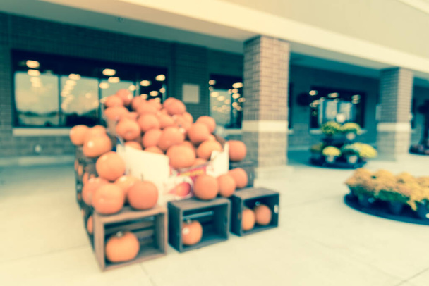 Filtered image blurry background Halloween pumpkins and flowers at supermarket entrance - Photo, Image