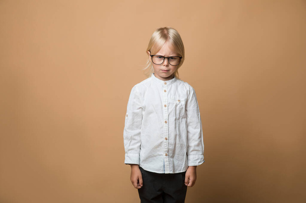 A boy in glasses dressed in white shirt, black trousers thinks about serious plans. School - Фото, зображення