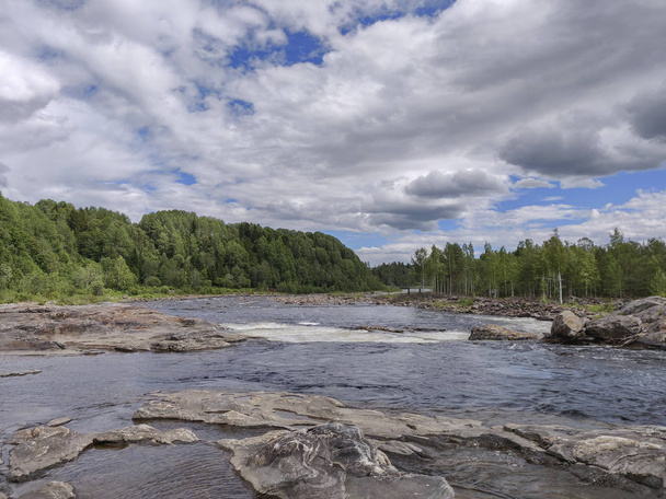 Acqua del fiume che passa vicino alla dura pietra marrone in una nuvolosa soleggiata da
 - Foto, immagini