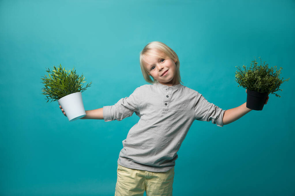 Un niño pequeño sosteniendo macetas con una planta verde. Niños y naturaleza. Conservar la naturaleza
 - Foto, imagen