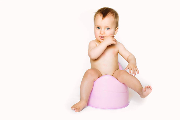 baby girl sits on a childrens pot, toilet on a white background - Фото, зображення