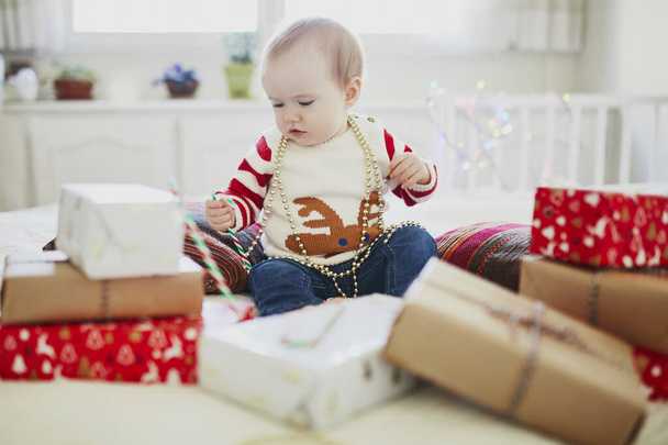 Happy little baby girl opening Christmas presents on her very first Christmas - Valokuva, kuva