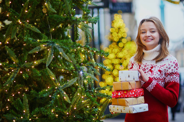 Happy young girl in holiday sweater with pile of Christmas presents - Photo, image