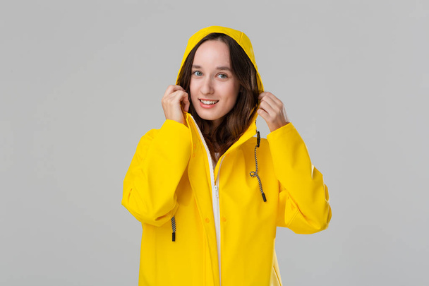 Smiling brunette girl in a yellow raincoat. Get ready for bad weather. - Фото, зображення