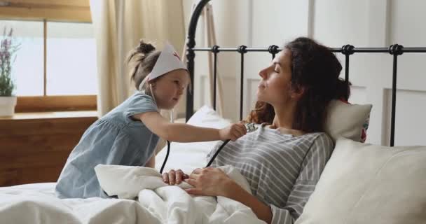 Cute girl playing as doctor nurse listening mom with stethoscope - Video