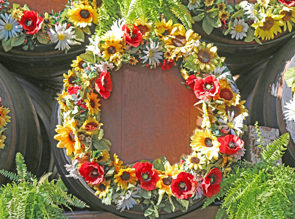 Винные бочки украшены венками осенних цветов
 - Фото, изображение