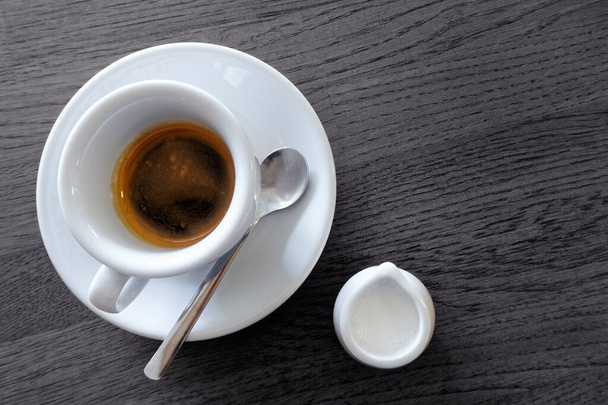 Classic italian single espresso in white cup next to a milk jug  - Fotó, kép