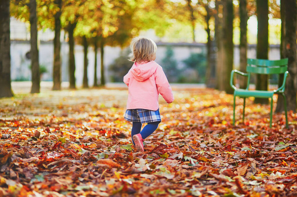 Urocza, wesoła dziewczynka biegająca w ogrodzie Tuileries w Paryżu, Francja - Zdjęcie, obraz