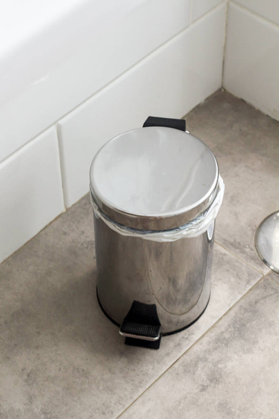 Metal silver garbage can with lid on the floor in the hotel bathroom with white tiles  on the wall. Bathroom modern luxury interior  - Photo, Image