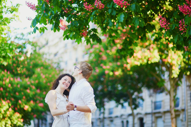 Happy romantic couple in Paris, hugging under pink chestnuts in full bloom - Foto, Imagen
