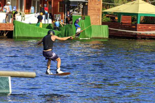 Ένας wakeboarder τρέχει μέσα από το νερό με μεγάλη ταχύτητα ξεπερνώντας διάφορα εμπόδια. - Φωτογραφία, εικόνα
