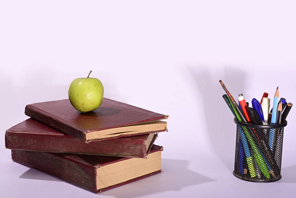 Зелене яблуко на книзі з підставкою для ручки ізольовано на дерев'яному фоні
 - Фото, зображення