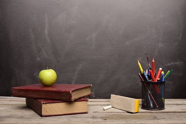Книги и образовательные принадлежности на деревянном столе в классе
 - Фото, изображение