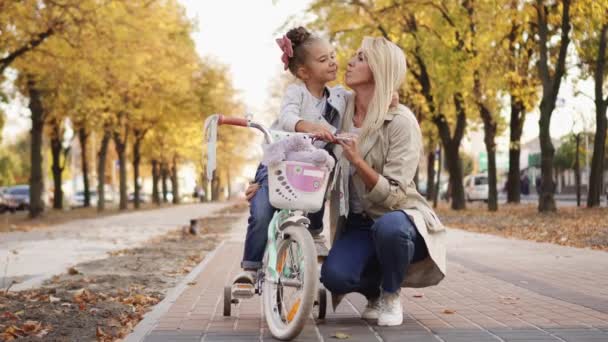 Niña abraza y besa a su madre mientras camina en el parque
 - Metraje, vídeo