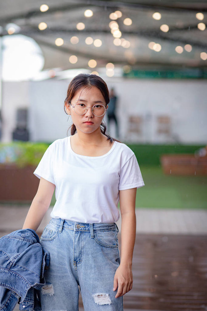Nerdy Asian woman in white t-shirt and ripped jeans - Photo, image