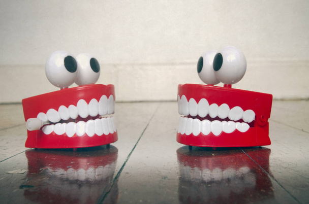 two platic teeth toys chatting on a old wooden floor - Photo, Image