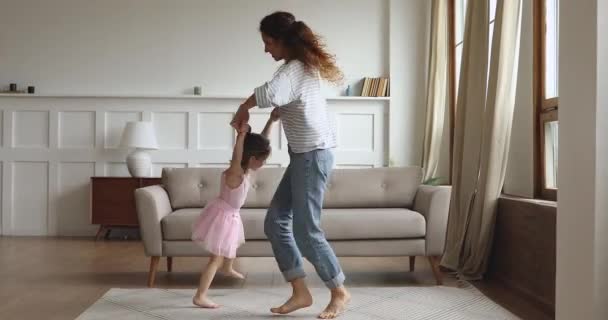 Active mom lifting spinning kid daughter dancing in living room - Metraje, vídeo