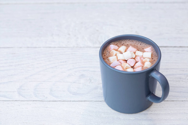 Hot chocolate with small pink and white marshmallows in a blue-g - Φωτογραφία, εικόνα