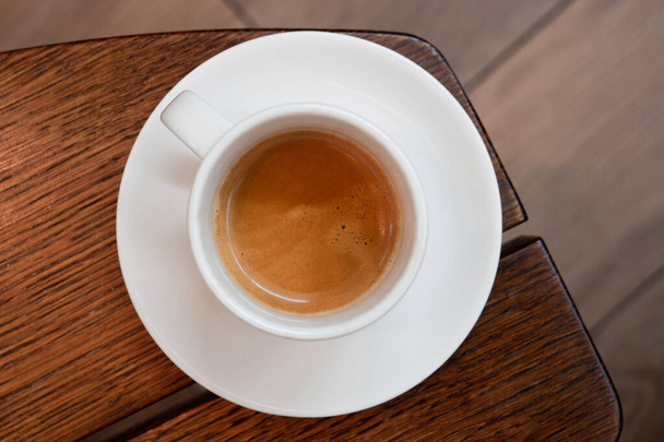 Italian espresso in a white ceramic cup with saucer on a brown w - Fotografie, Obrázek