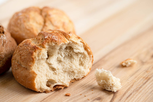 Broken round rustic white bread roll next to two round bread rol - Foto, Imagem