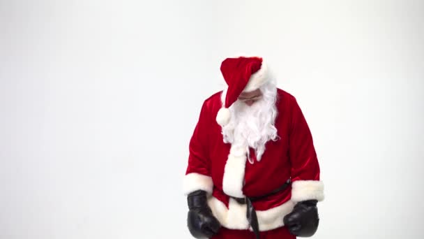 Christmas. Santa Claus on a white background wears black boxing gloves and fulfills punches. Kickboxing, fighter. - Materiał filmowy, wideo