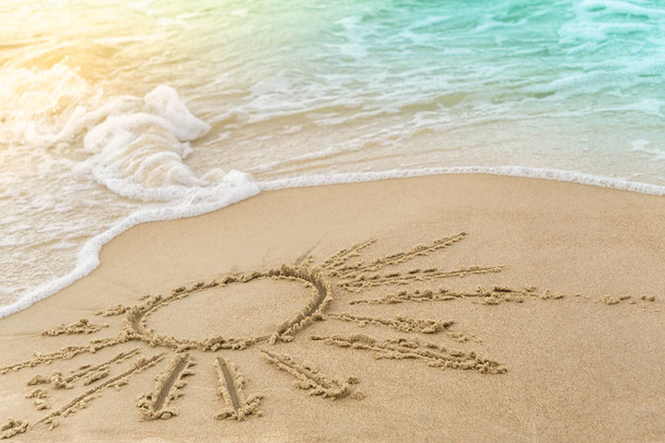 O símbolo do sol que desenha na praia de areia, cobrindo a espuma onda azul-turquesa do mar. Conceito de férias de verão ensolarado
. - Foto, Imagem