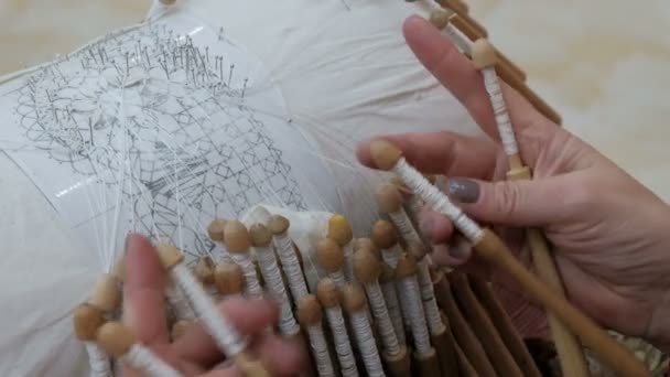 Hand Weaving Lace. The craftswoman spins a beautiful pattern from thin silk threads. The ancient tradition of the lace pillow. Close-up of female hands quickly fingering coils between fingers. - Záběry, video