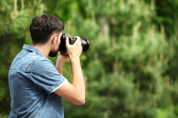Photographer taking photo with professional camera in park. Space for text - Foto, Imagen