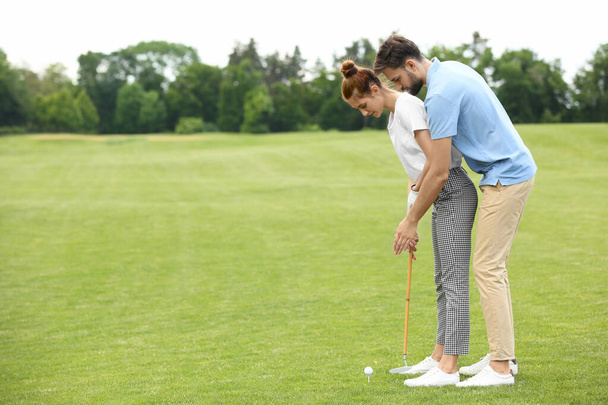 Coach teaching woman to play golf on green course - 写真・画像
