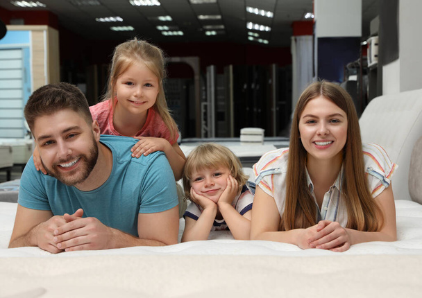 Familia feliz acostada en un nuevo colchón ortopédico en la tienda
 - Foto, Imagen