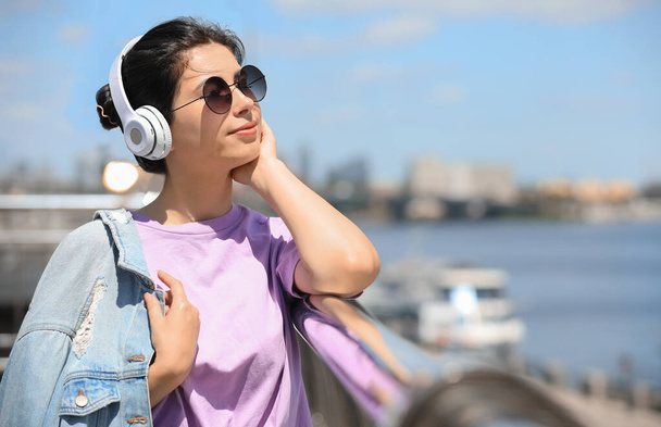 Young woman with headphones listening to music outdoors. Space for text - Fotó, kép