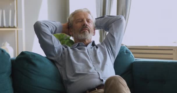 Healthy serene senior man napping relaxing on couch at home - Video, Çekim