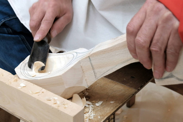 Делаю деревянную ложку. Мужские руки с инструментом крупным планом. Традиционное ремесленное деревообработка или хобби
. - Фото, изображение