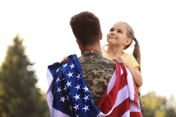 Father in military uniform with American flag and his daughter at sunny park - Foto, Bild
