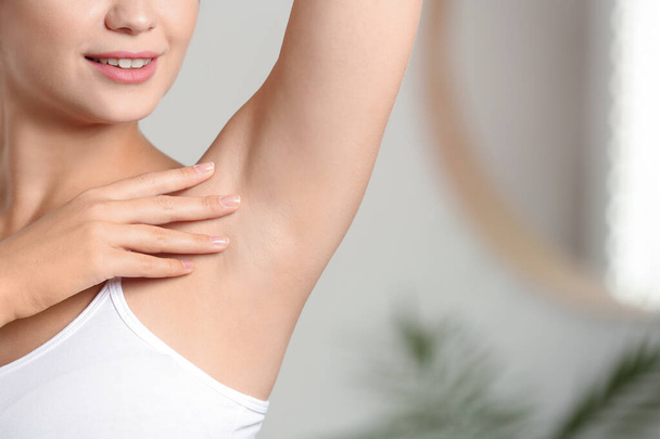 Young woman with smooth clean armpit indoors, space for text. Using deodorant - Foto, Imagem