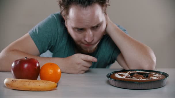 Man cannot choose between fruits and cake - Footage, Video