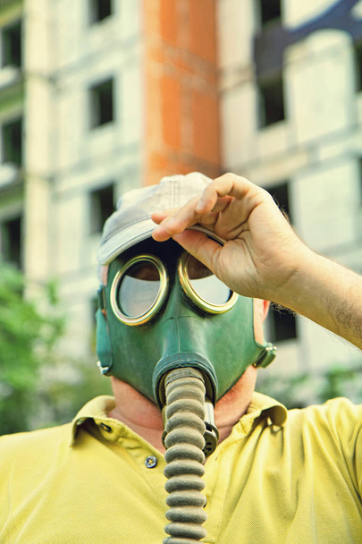 Men in gas mask and cap closeup on destroyed building background - Foto, imagen
