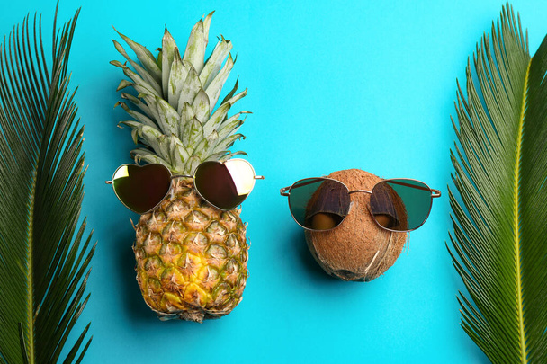 Pineapple and coconut with sunglasses on blue background, flat lay - Fotó, kép