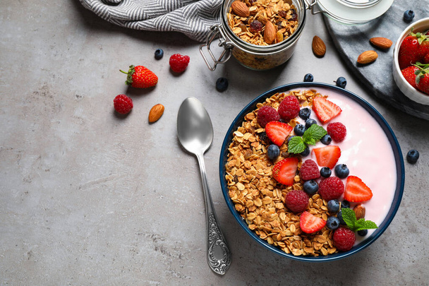 Healthy homemade granola with yogurt on grey table, flat lay. Space for text - Foto, afbeelding